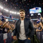Zac Efron walking through Patriots fans at Gillette Stadium with Texans logo behind him and fans cheering